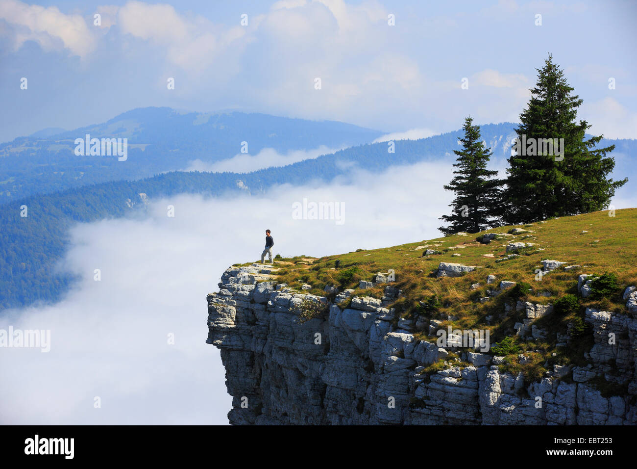 Uomo in piedi sul bordo di un ripido fronte di roccia naturale cirque Creux du Van, Svizzera Schweizer Giura, Neuchâtel Foto Stock