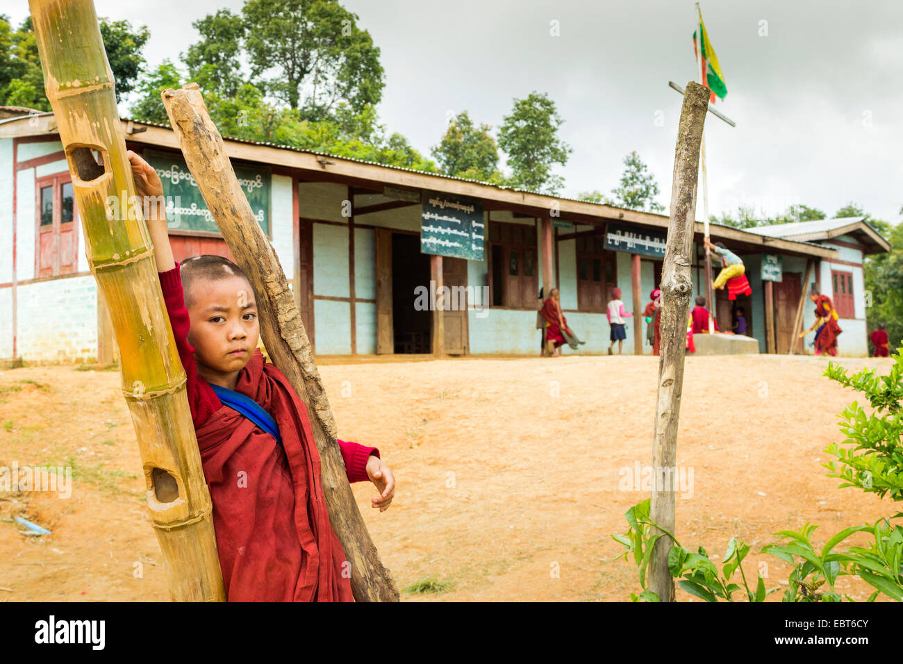Un ragazzo giovane monaco è in piedi al di fuori del suo edificio scolastico in Birmania, Myanmar, sud-est asiatico Foto Stock