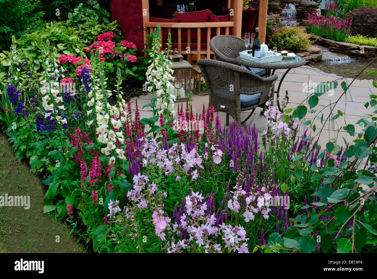 Il patio riflettente di un giardino acquatico con fiori colorati in border Foto Stock