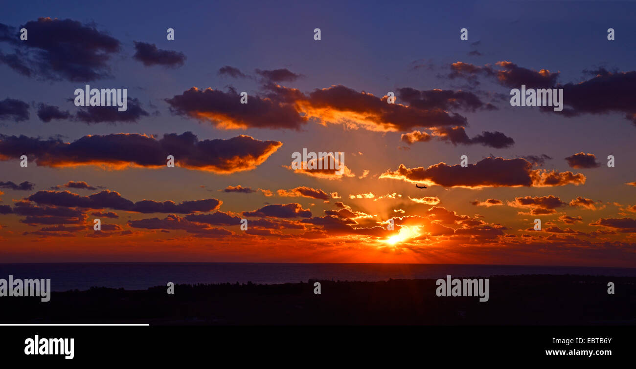 Un impressionante e colorato tramonto oltre l'aeroporto Paphos con un aereo in arrivo a terra Foto Stock