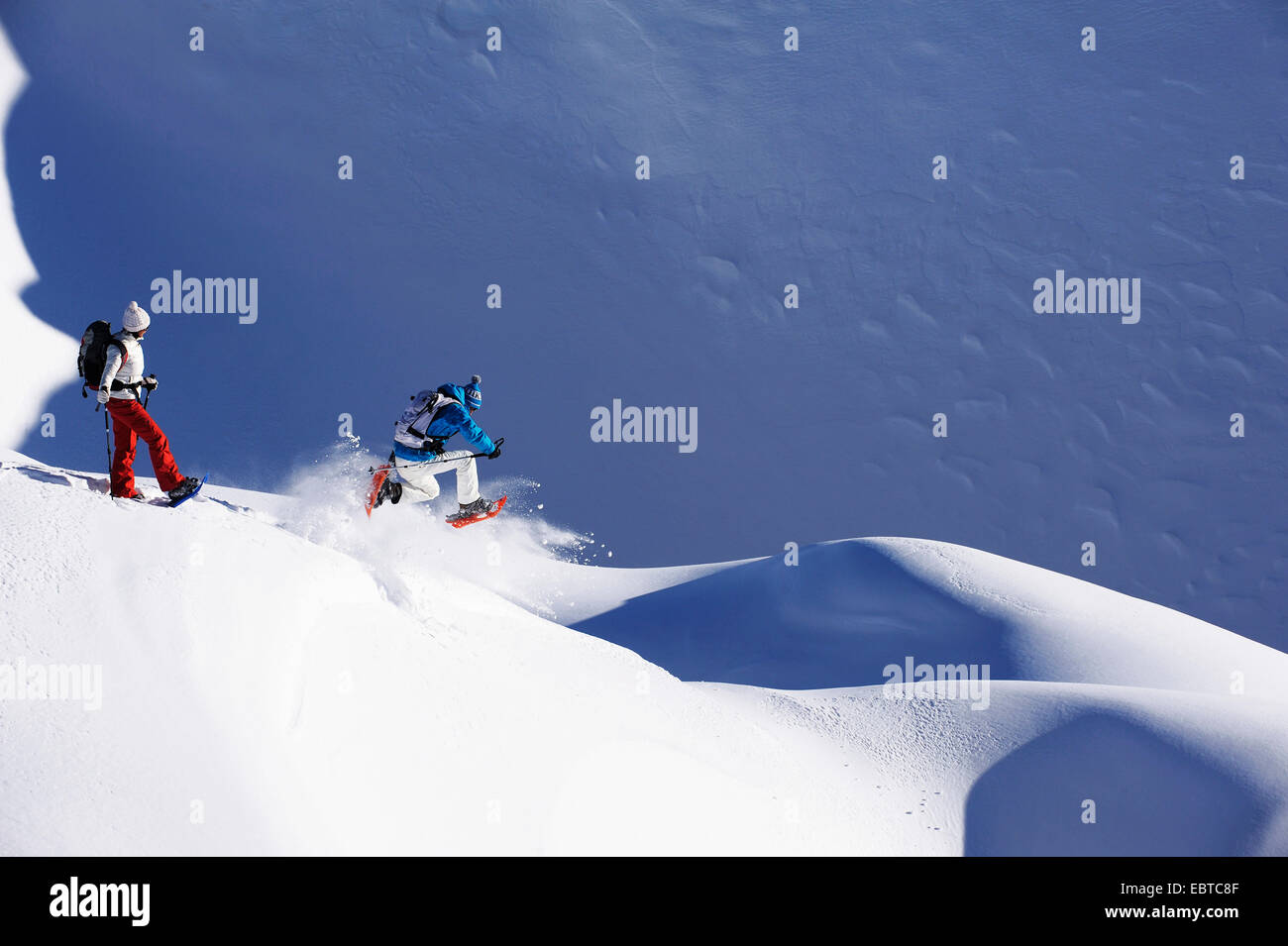 Uomo e donna con le racchette da neve su una coperta di neve pendenza, Francia Foto Stock