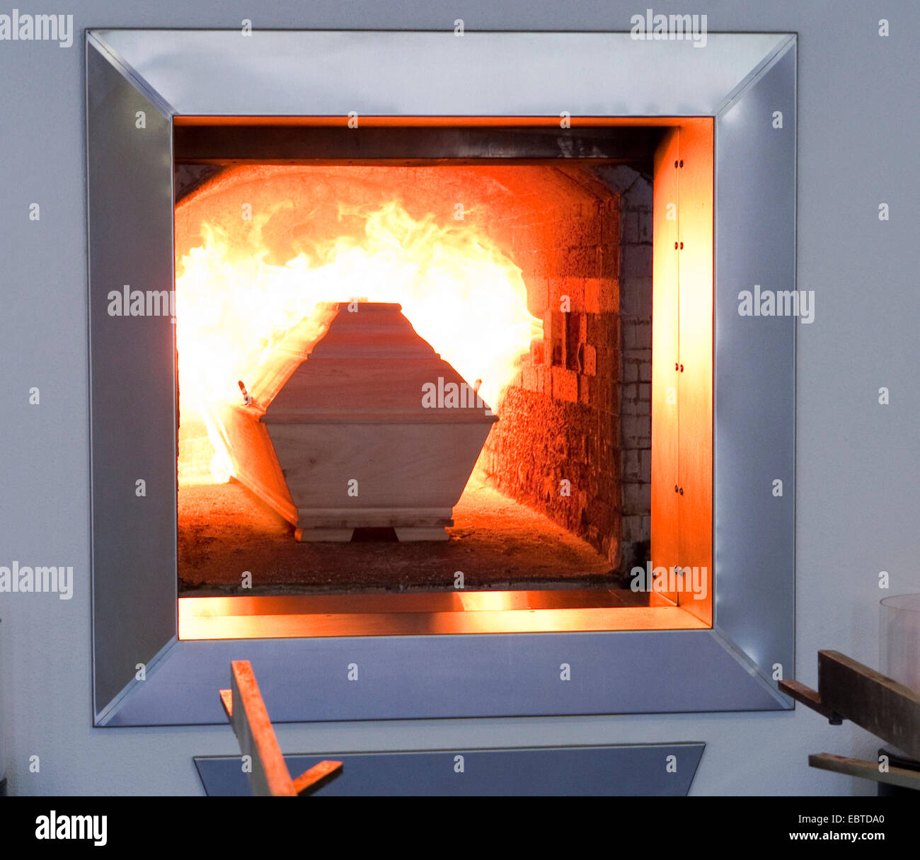 Membro del personale di un crematorio di agitazione è il fuoco nel forno Foto Stock