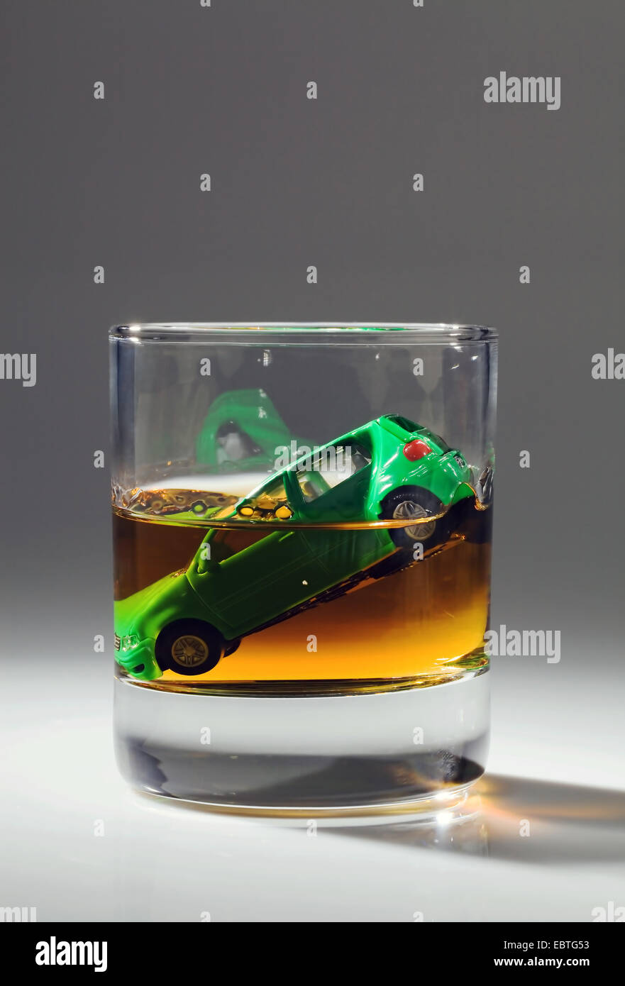 Giocattolo auto sprofonda in un bicchiere di alcool Foto Stock