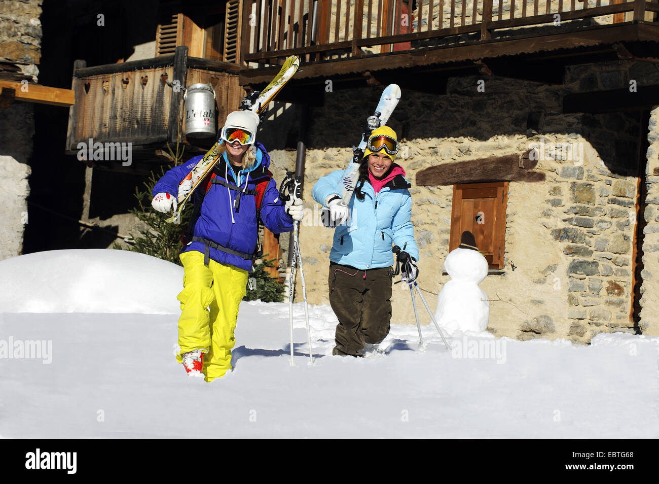 Due donne con attrezzature da sci passeggiate attraverso il villaggio di montagna, Francia, Savoie, Sainte Foy Tarentaise Foto Stock