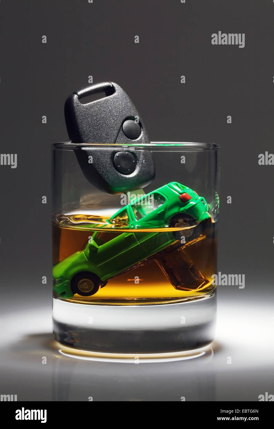 Macchina giocattolo e chiave auto sprofonda in un bicchiere di alcool Foto Stock