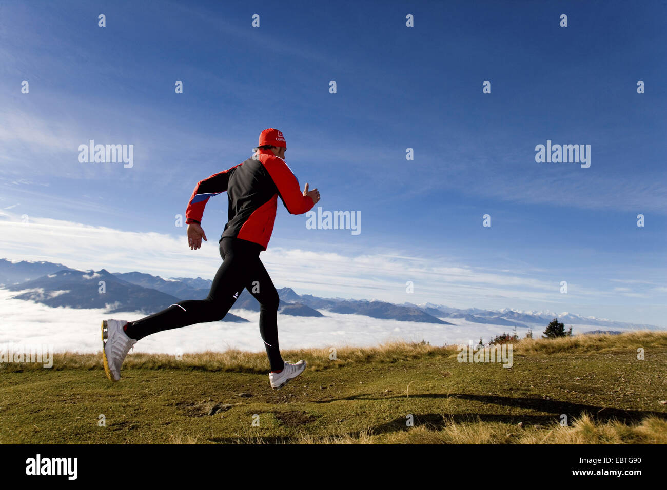 L'uomo jogging in un pascolo alpino, Italia Foto Stock
