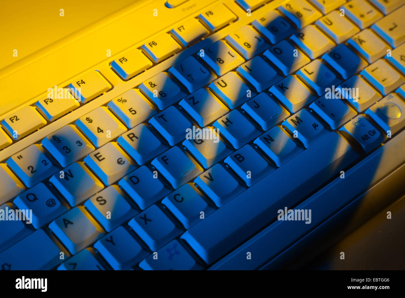 La tastiera del computer e l'ombra di una mano, il furto di dati Foto Stock