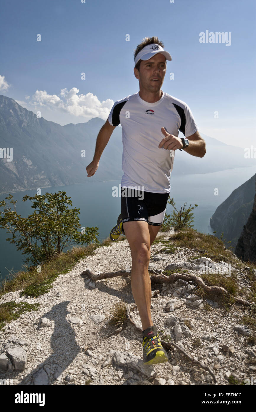 L'uomo jogging in montagna in alto sopra il Lago di Garda, Italia Foto Stock