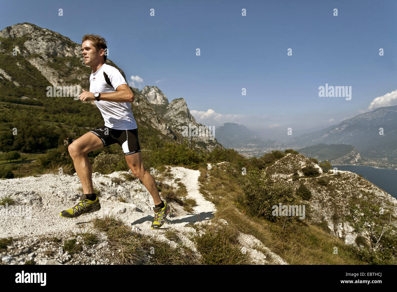 L'uomo jogging in montagna in alto sopra il Lago di Garda, Italia Foto Stock