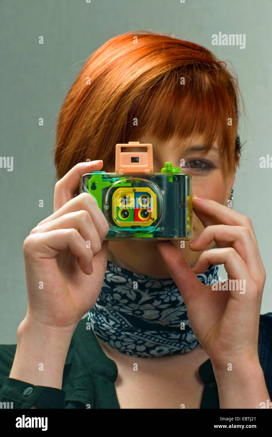 Giovane donna redheaded scattare foto con una fotocamera Lomo Foto Stock