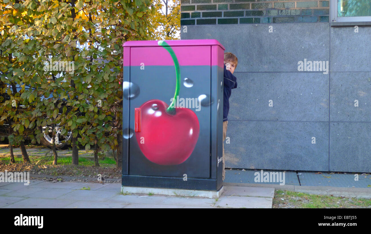 Ragazzo nascosto dietro un quadro a muro, dipinta con una ciliegia immerso in una bevanda, in Germania, in Renania settentrionale-Vestfalia, Duesseldorf Foto Stock