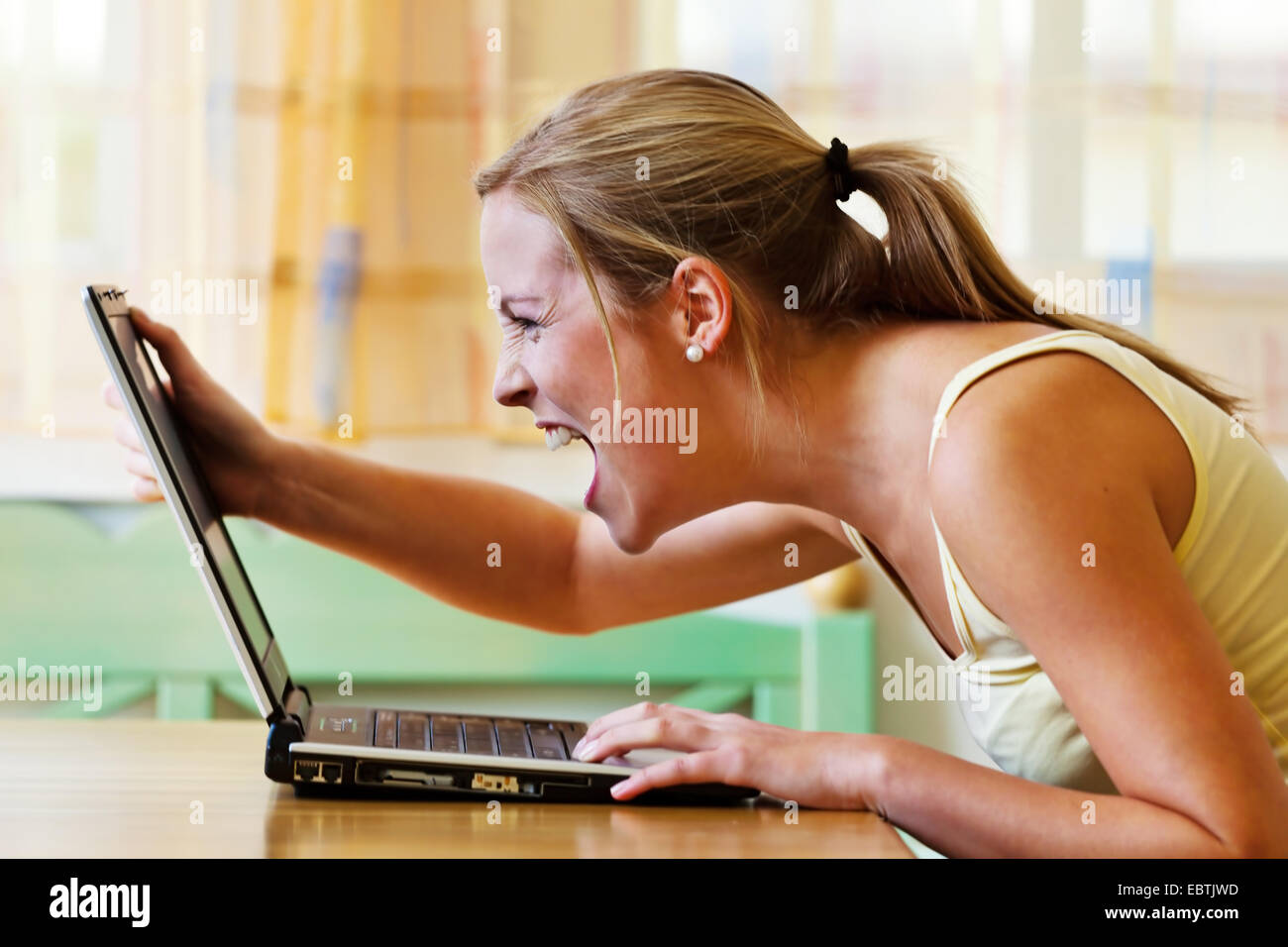 Furious donna grida al suo computer portatile Foto Stock