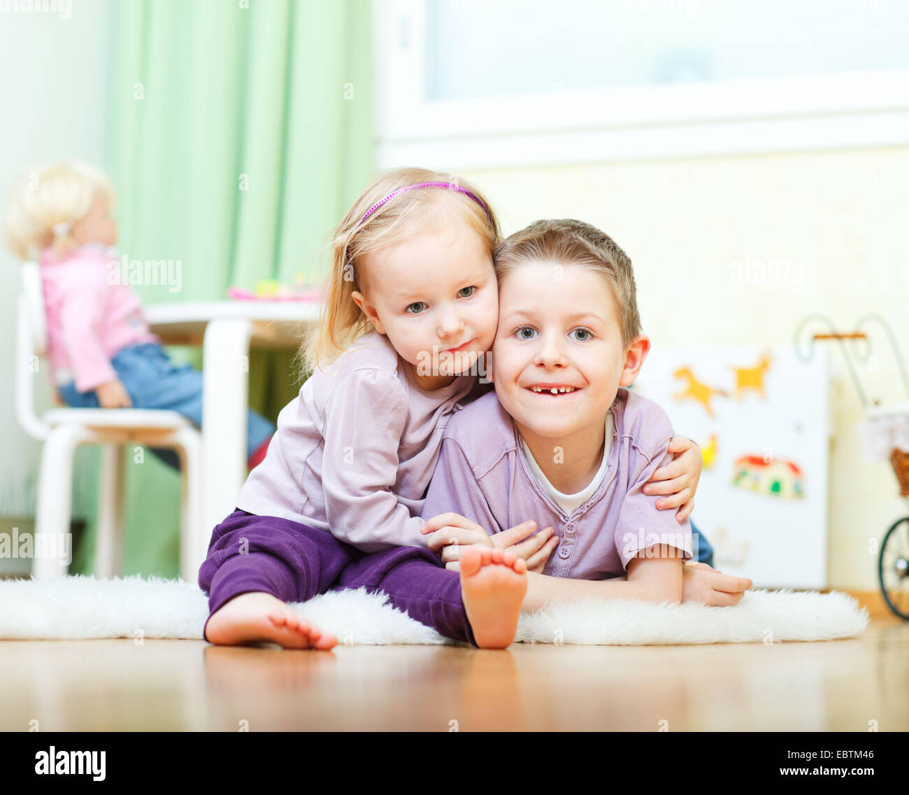 Fratello e Sorella felicemente abbracciando sul pavimento vivaio Foto Stock
