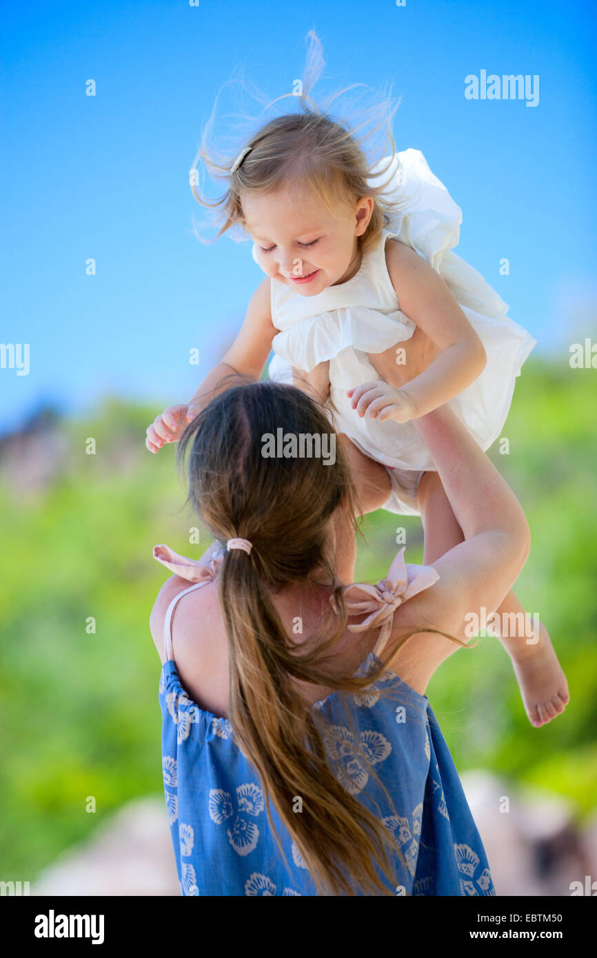 Giovane madre rollicking circa con la sua piccola figlia all'aperto su un il giorno di estate Foto Stock