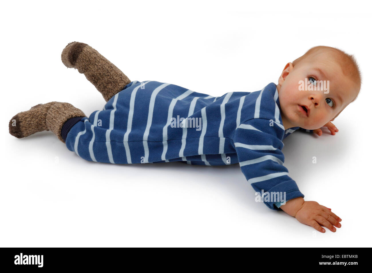 Little Boy indossando romper striped suit giacente a terra e ruotare la testa Foto Stock