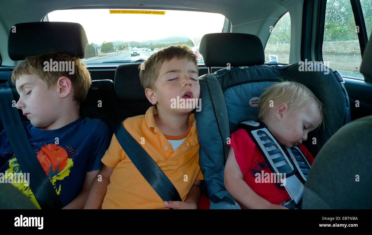 Tre ragazzi piccoli dormendo fianco a fianco sul sedile posteriore di una macchina Foto Stock