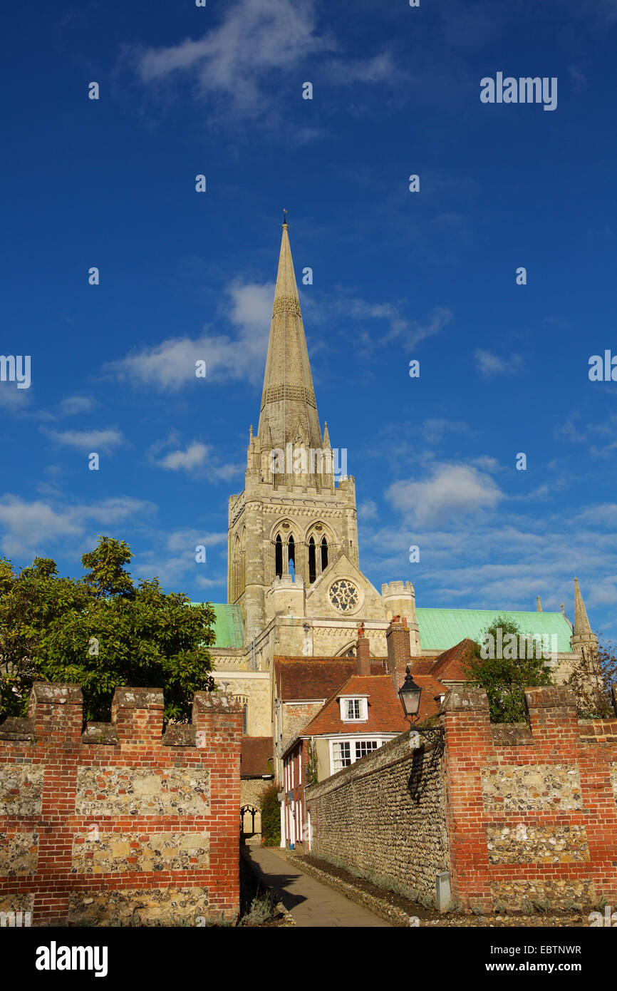 Vista della Cattedrale di Chichester guglia dietro la pietra e un muro di mattoni. Guardando verso il basso il percorso di monaci con imponente muro di pietra focaia. Foto Stock