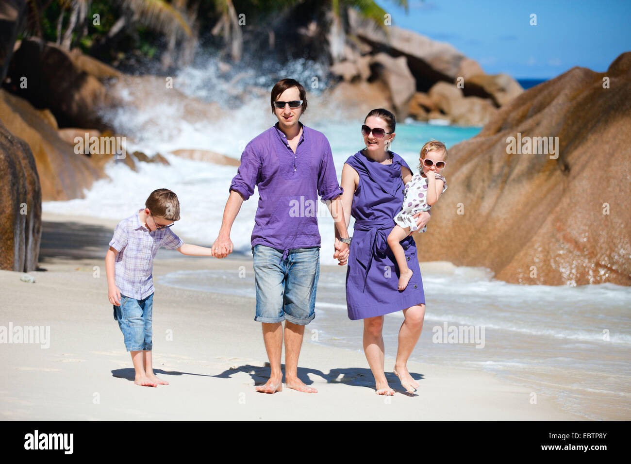 Giovane famiglia con due bambini passeggiate lungo la spiaggia tropicale, Seicelle Foto Stock