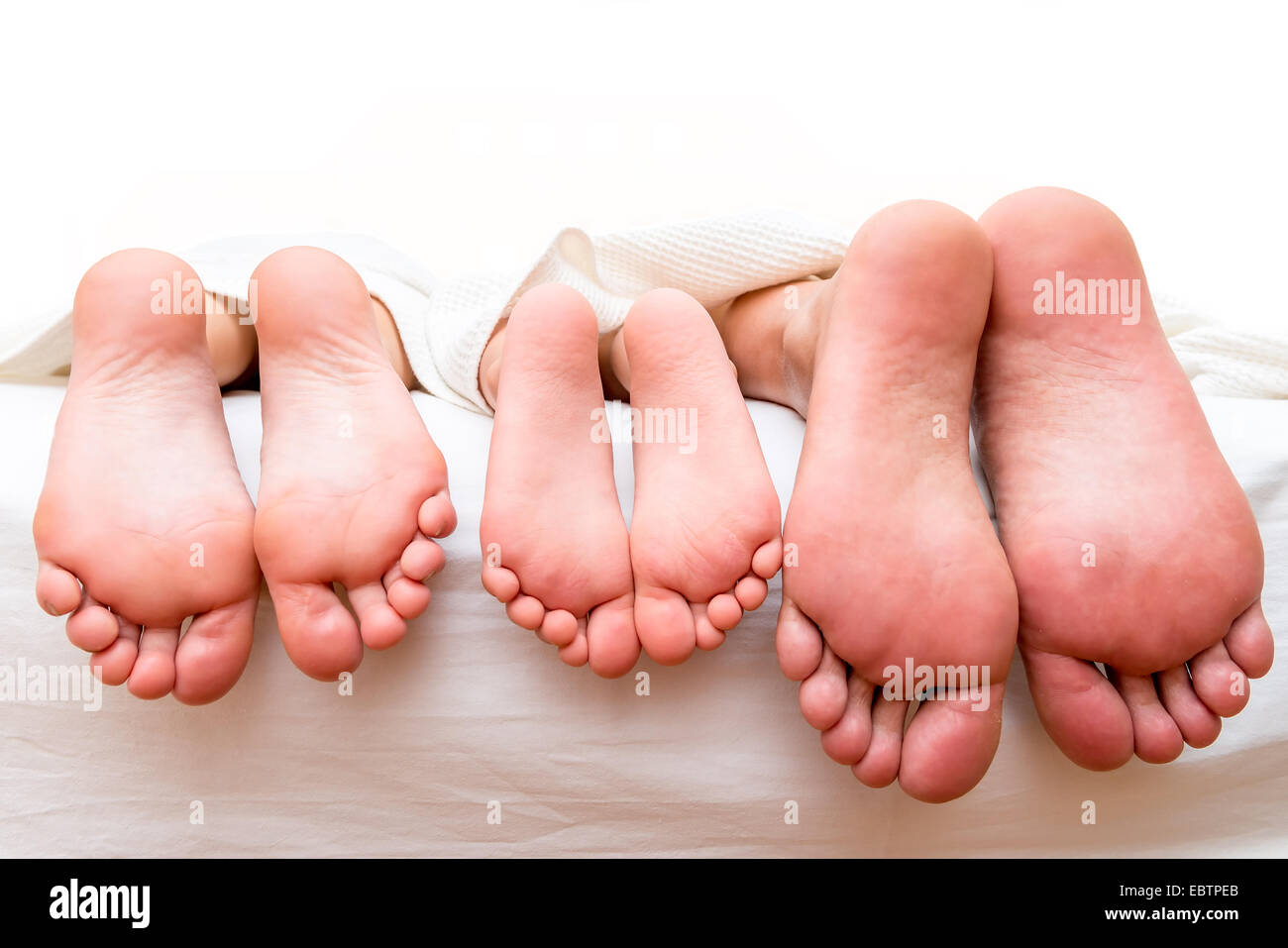 Piedi di genitori e figli sul letto di close-up Foto Stock