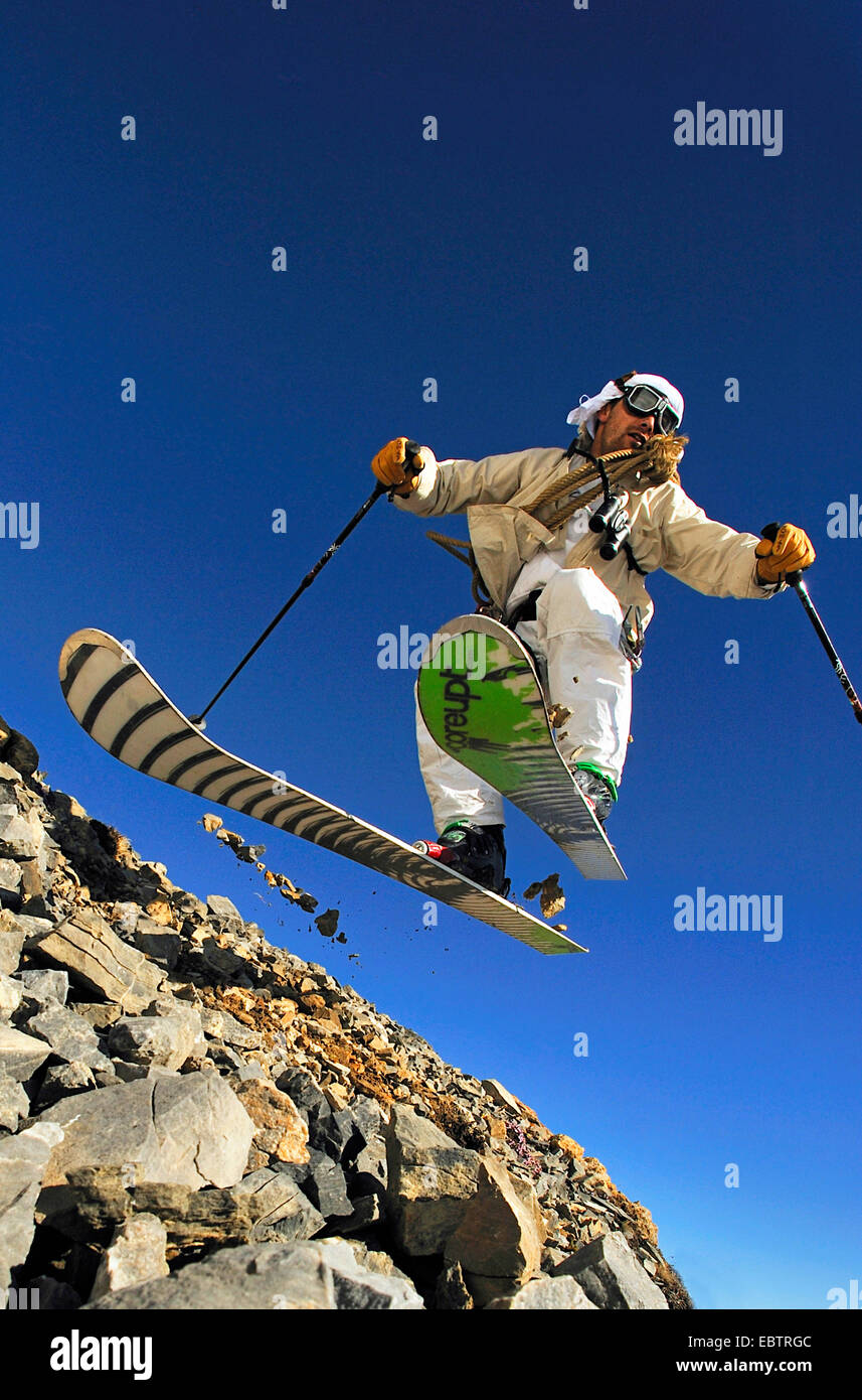 Sciatore freeride dissimulata come oldfashioned avventuriero in discesa sul pendio roccioso Foto Stock
