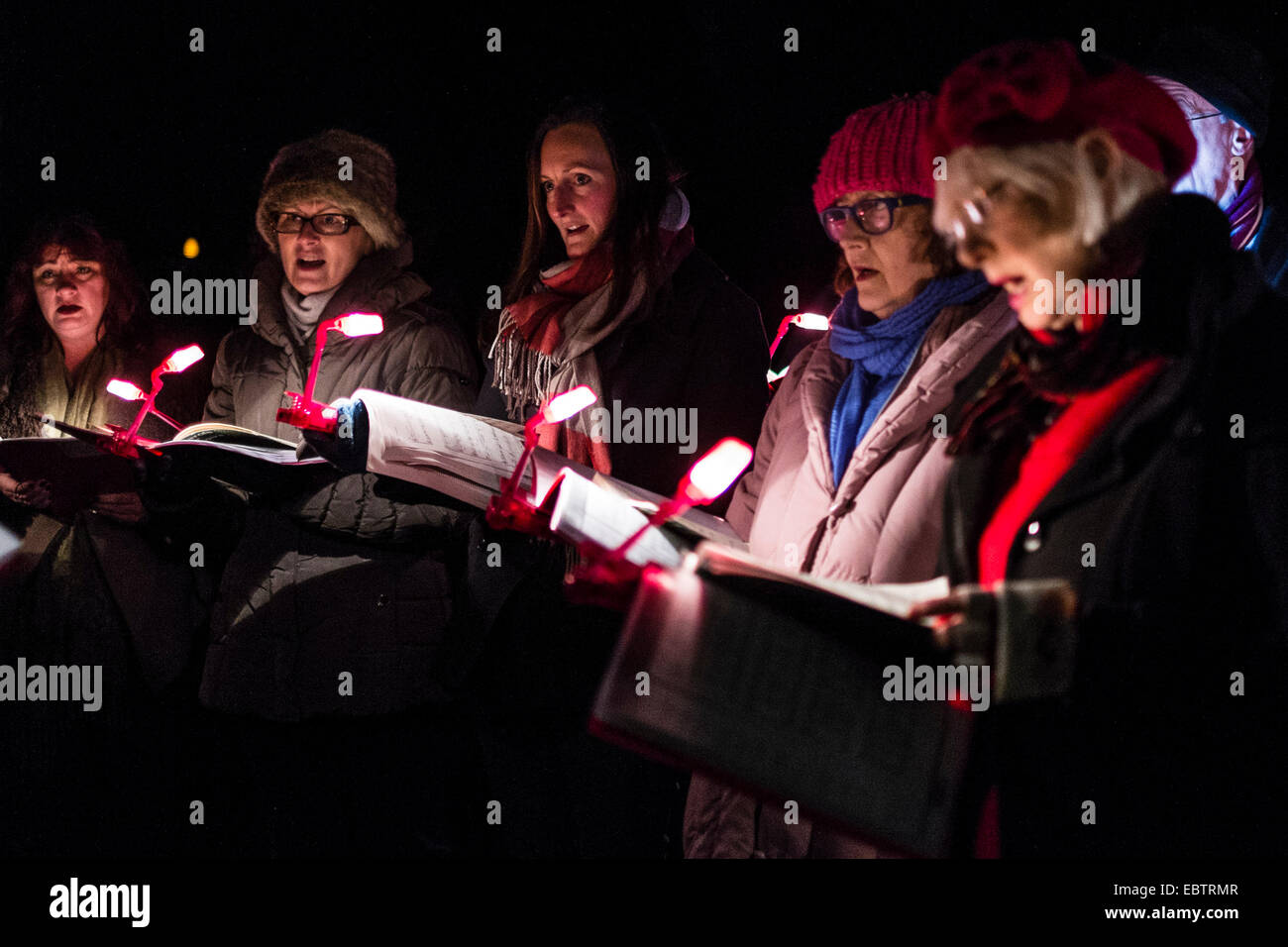 Wakehurst Place, Sussex, Regno Unito. 4 dicembre, 2014. Il Regno Unito più alti Living Christmas Tree è acceso durante il Glow selvaggio a Wakehurst. La 135ft Sierra Redwood California tree è illuminato da luci 1800. La serata ha inoltre presentato una lanterna accesa a piedi attraverso il giardino che termina in corrispondenza di una caratteristica di fuoco da "e" ora chiamato "oro, incenso e mirra" . Immagine mostra carol cantanti ai piedi dell'albero. Credito: Julie Edwards/Alamy Live News Foto Stock