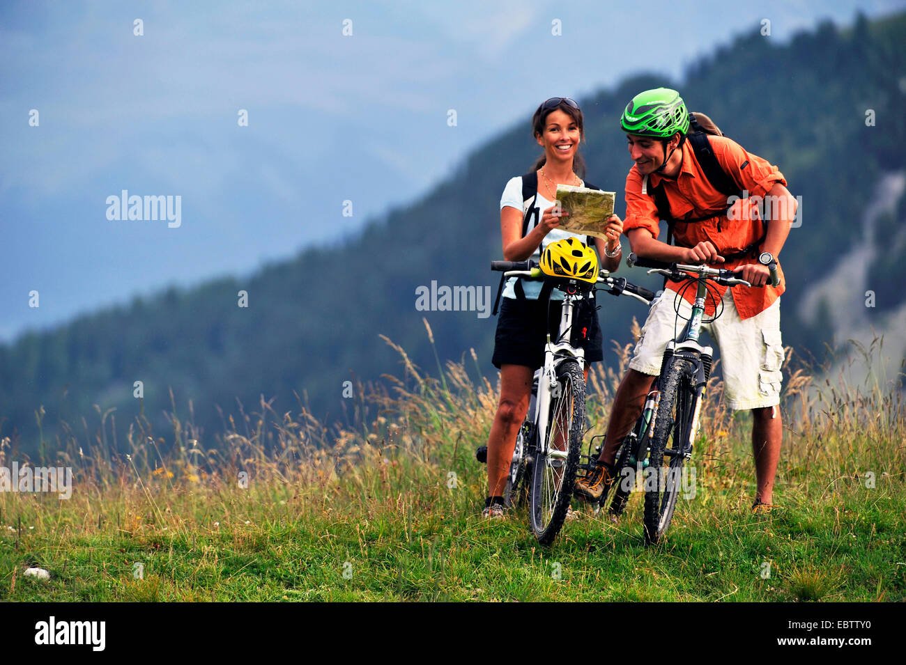 Due mountain bike cercando su una mappa del percorso nelle Alpi, Francia, Savoie, Parco Nazionale della Vanoise, La Plagne Foto Stock