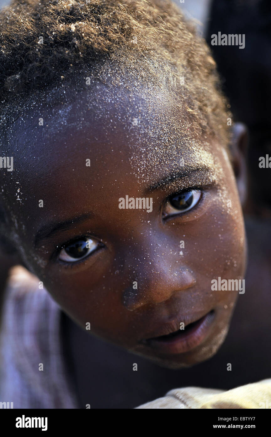 Poco di carnagione scura ragazzo con sabbia sulla faccia rivolta alla fotocamera, Madagascar, Nosy Be Foto Stock