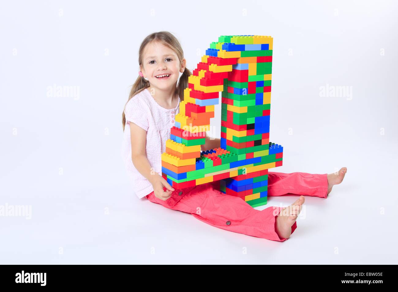 Quattro-anno-vecchia ragazza con un gran numero '4' costruito di mattoncini Lego Foto Stock