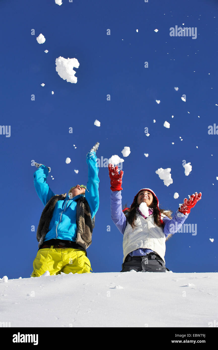 Due giovani ragazze frolicly gettando la neve in aria di fronte a un cielo blu, Francia Foto Stock
