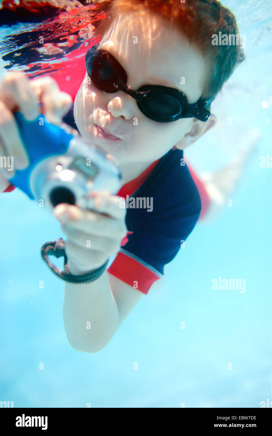 Un ragazzino con nuoto googles scattare foto sotto l'acqua Foto Stock