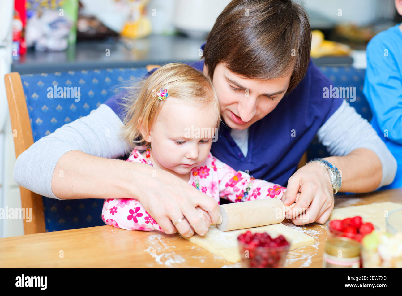 Padre la cottura biscotti con la sua piccola figlia Foto Stock