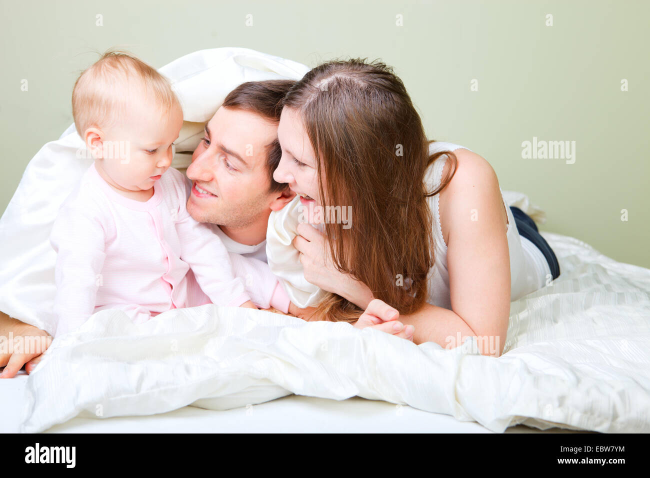 Famiglia giovane giacente in letto con piccola figlia Foto Stock