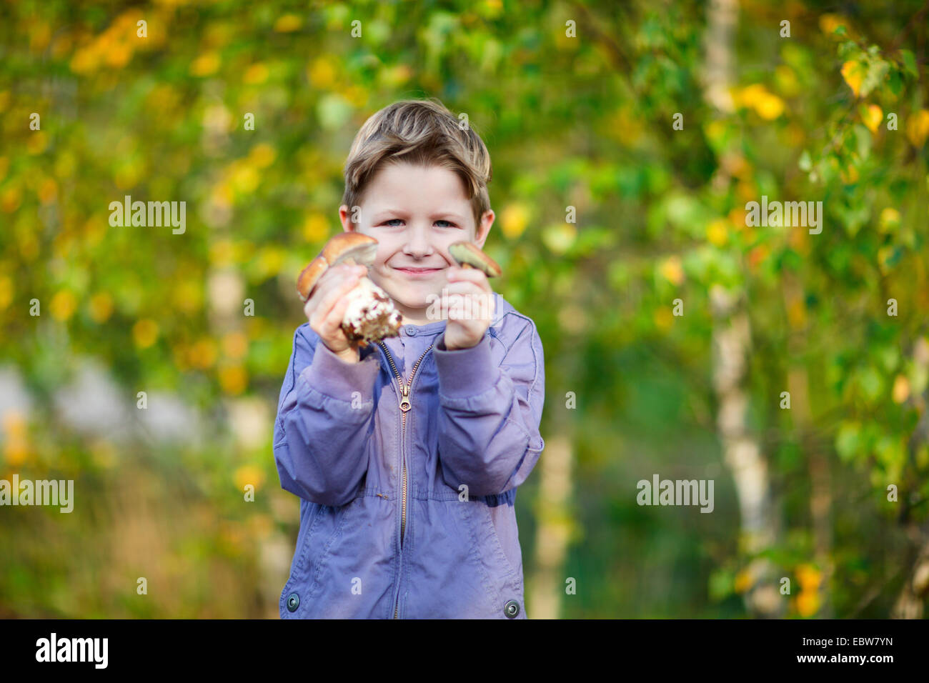Un ragazzino che mostra due funghi selvatici Foto Stock
