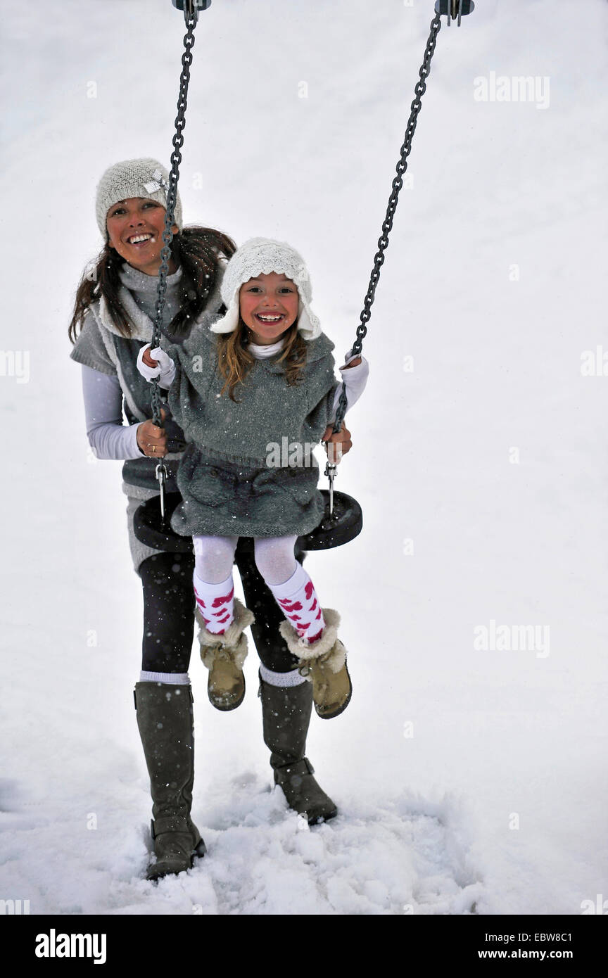 Madre e figlia su altalena in snow Foto Stock