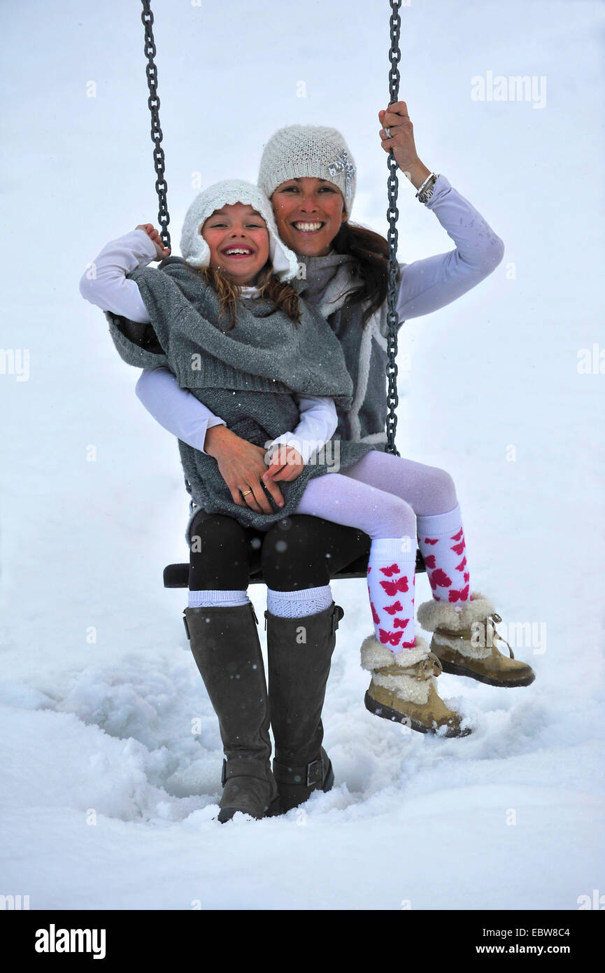 Madre e figlia su altalena in snow Foto Stock