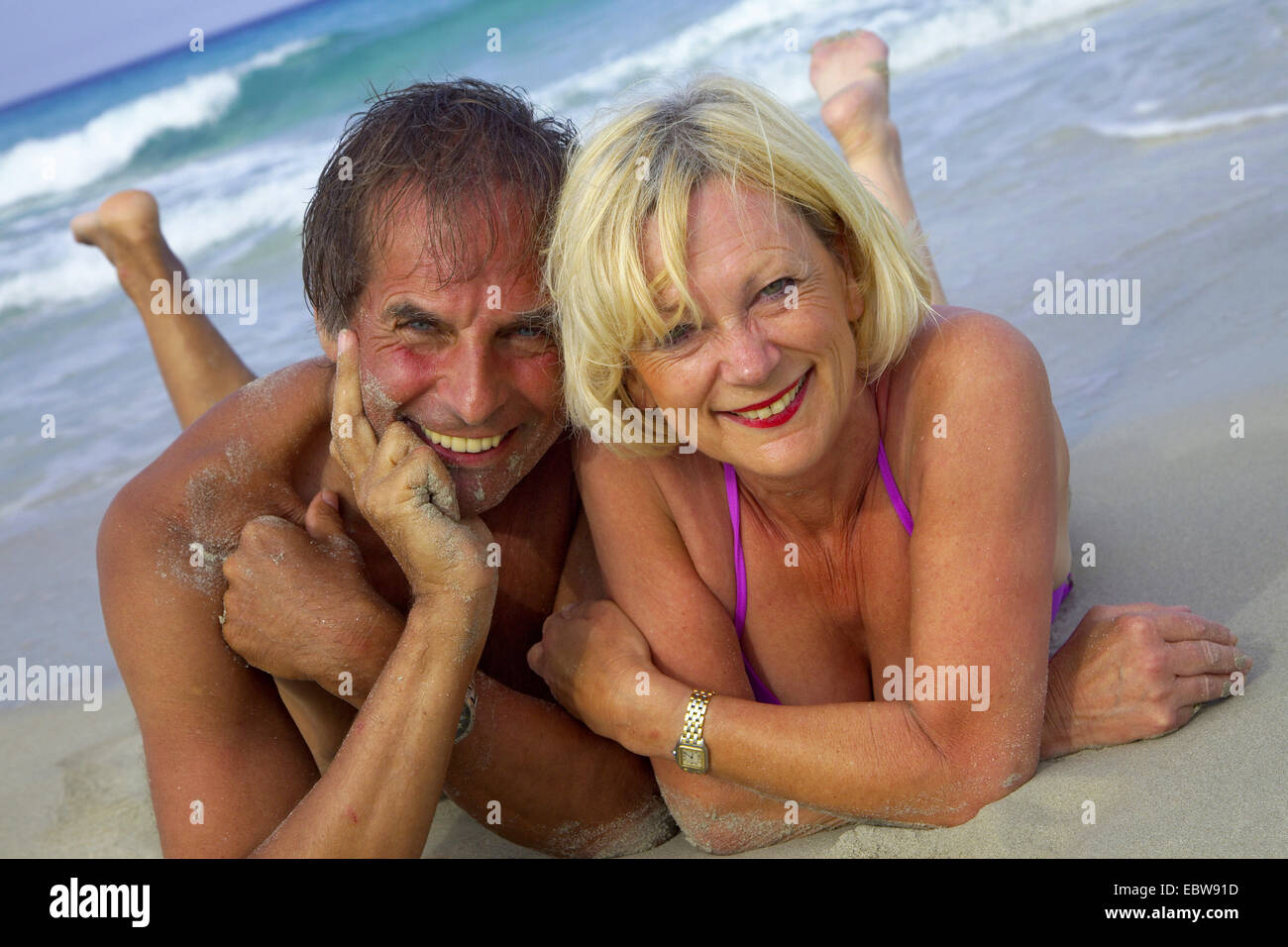 Coppia di anziani che giace sulla spiaggia sabbiosa, Balearen, Ibiza Foto Stock