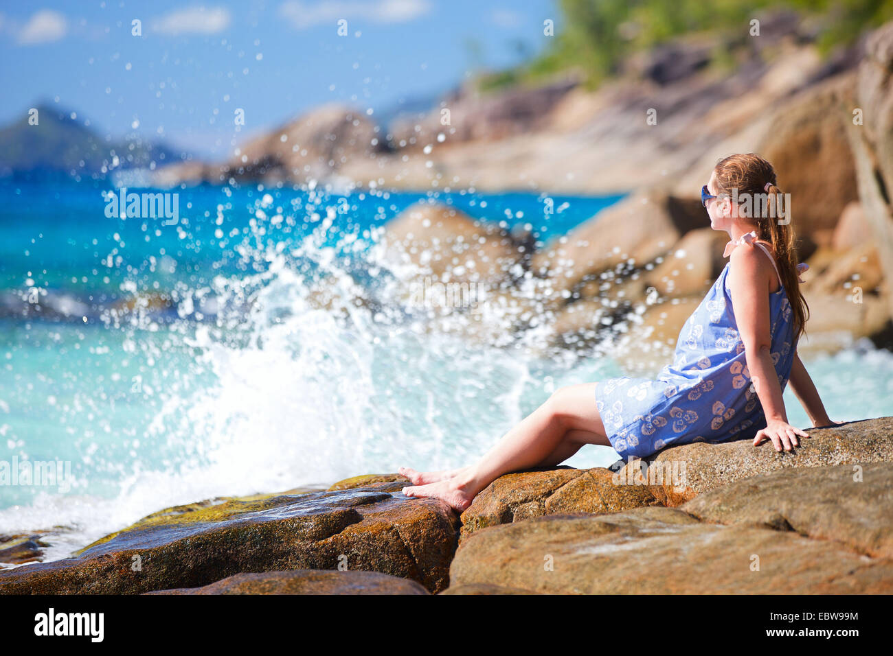 Giovane donna sdraiata sulla roccia costiera Foto Stock