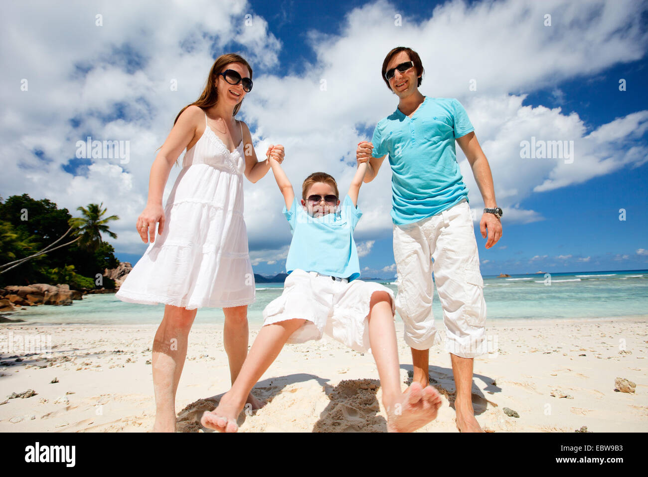 Felice giovane famiglia sulla spiaggia tropicale Foto Stock