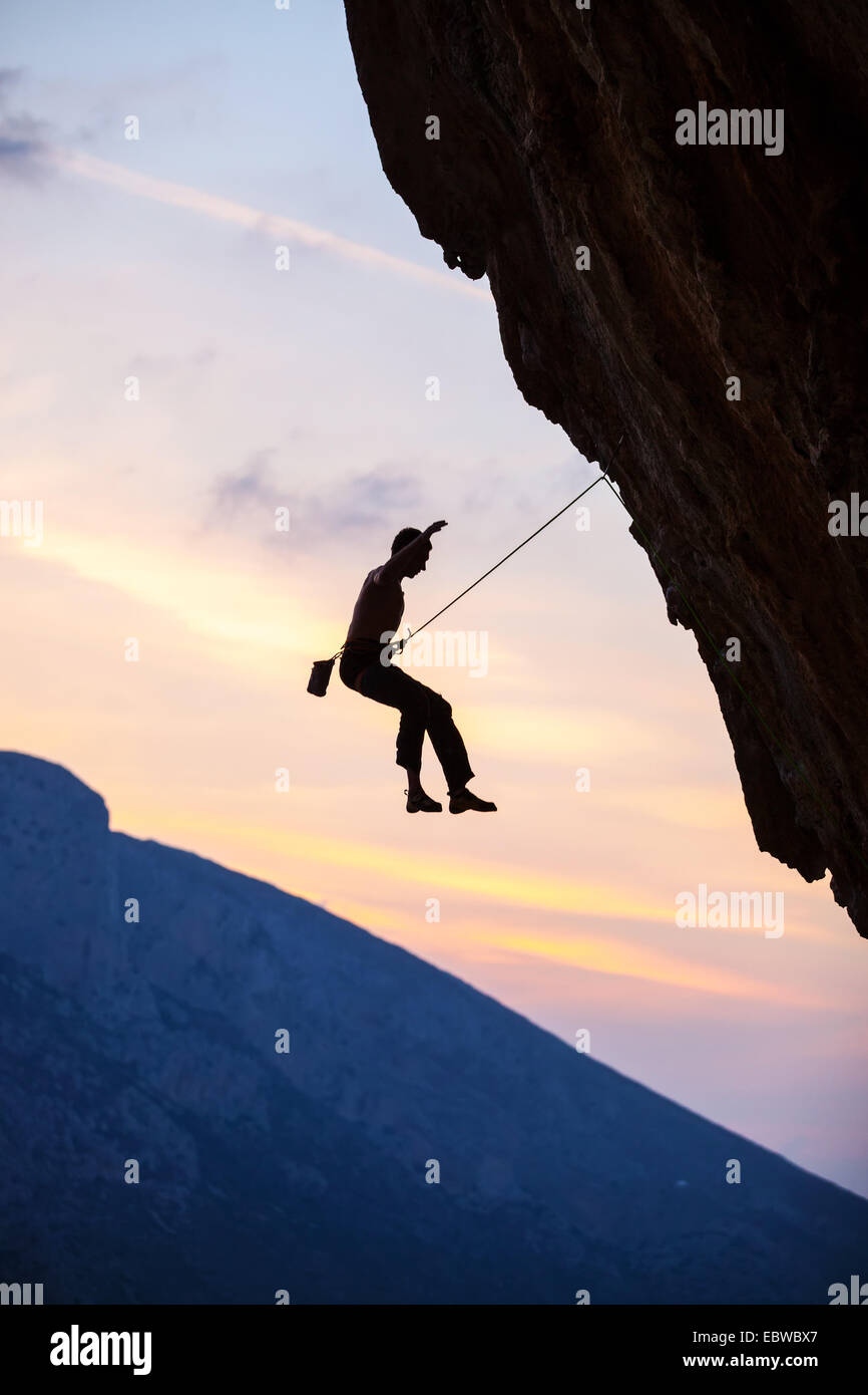 Silhouette di un rocciatore la caduta di una scogliera mentre arrampicata di piombo Foto Stock