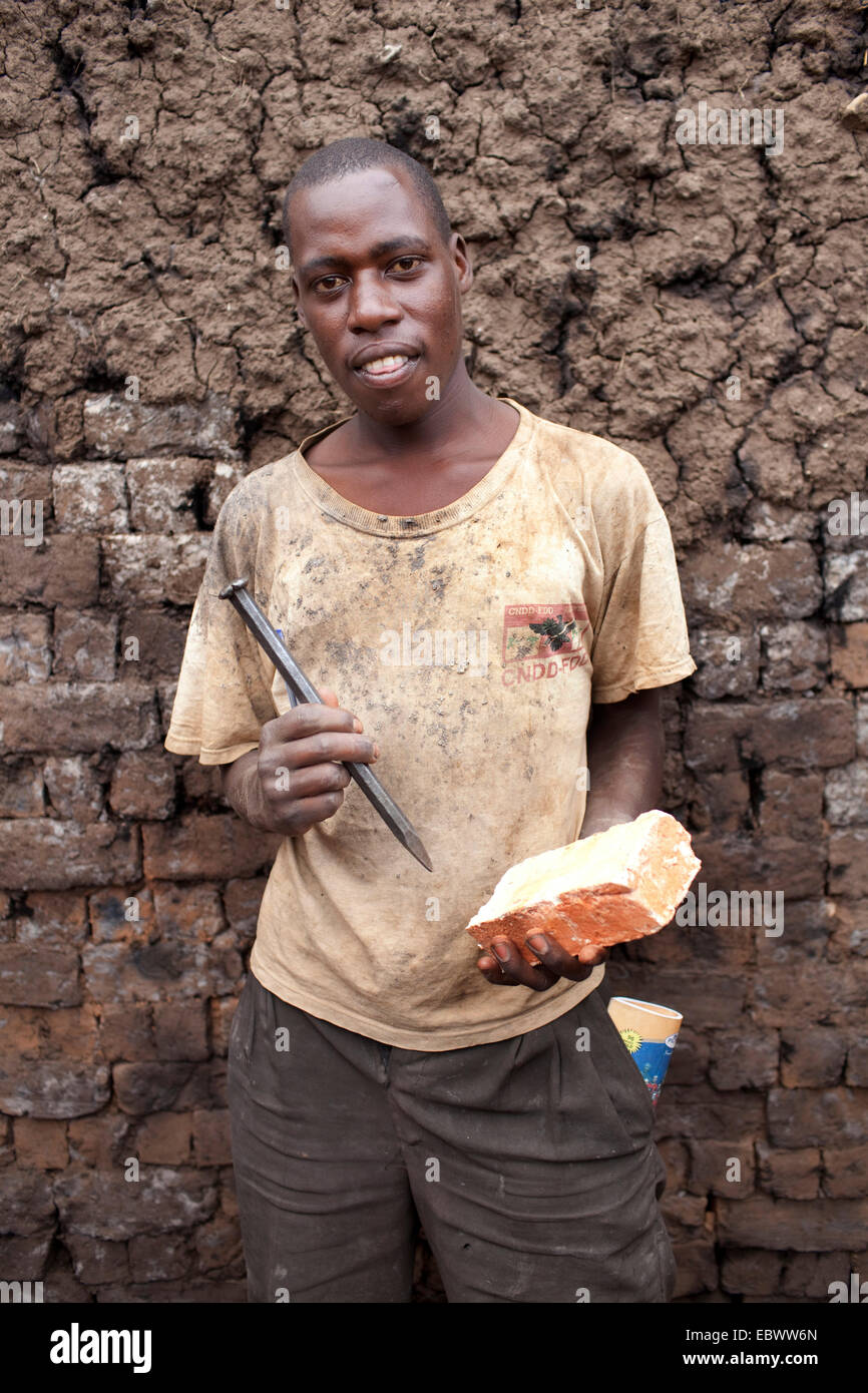 Lavoratore con mattoni di argilla e il bit in piedi di fronte ad una parete, Burundi, Karuzi, Buhiga Foto Stock