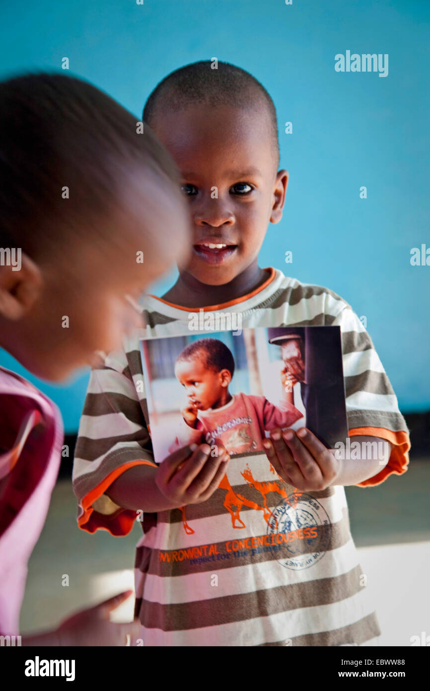 Little Boy è in possesso di una fotografia in mano con se stesso su di esso e con orgoglio che lo mostra a un amico, Burundi Bujumbura Mairie, Bujumbura Foto Stock