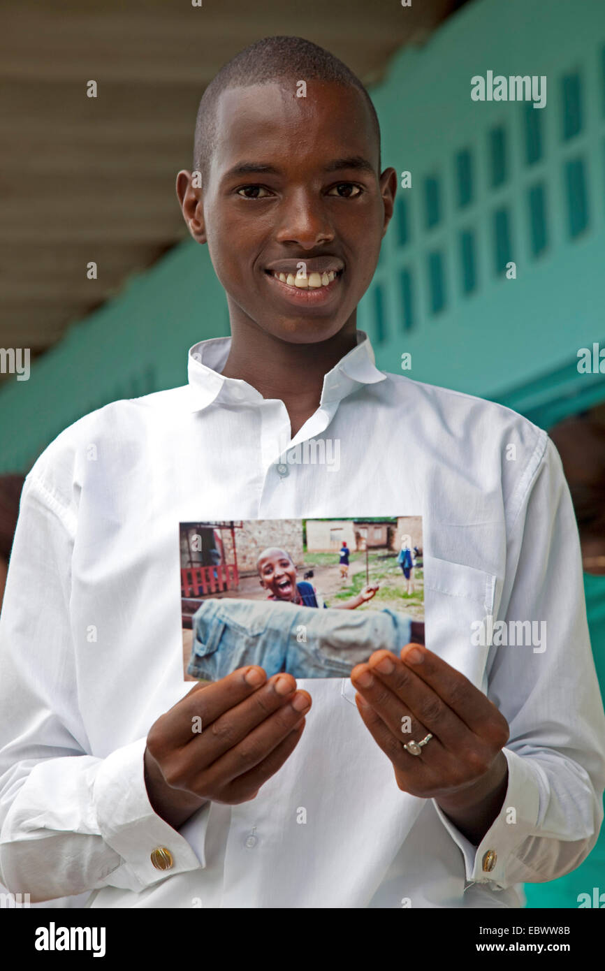 Il ragazzo è sempre sorridente mentre si tiene una fotografia in mano con se stesso su di esso, il Burundi Bujumbura Mairie, Bujumbura Foto Stock