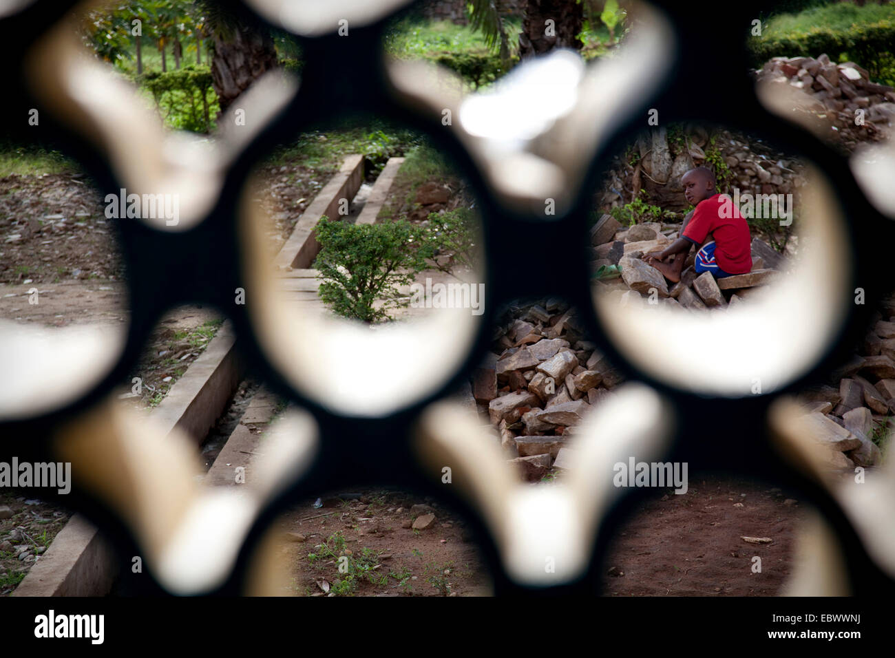 Ragazzo seduto sul mucchio di pietre sul sito dell orfanotrofio, Burundi Bujumbura Mairie, Bujumbura Foto Stock