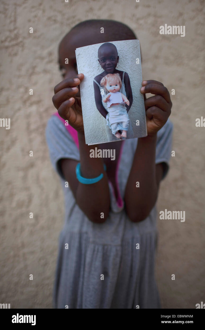 Bambina che mostra una foto dove ella tenendo una bambola, Burundi Bujumbura Mairie, Bujumbura Foto Stock