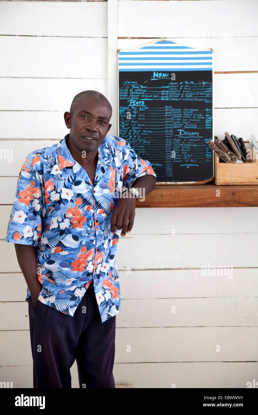 Uomo in piedi in un bancone con posateria e menu, Burundi, Bujumbura Mairie, Bujumbura Foto Stock