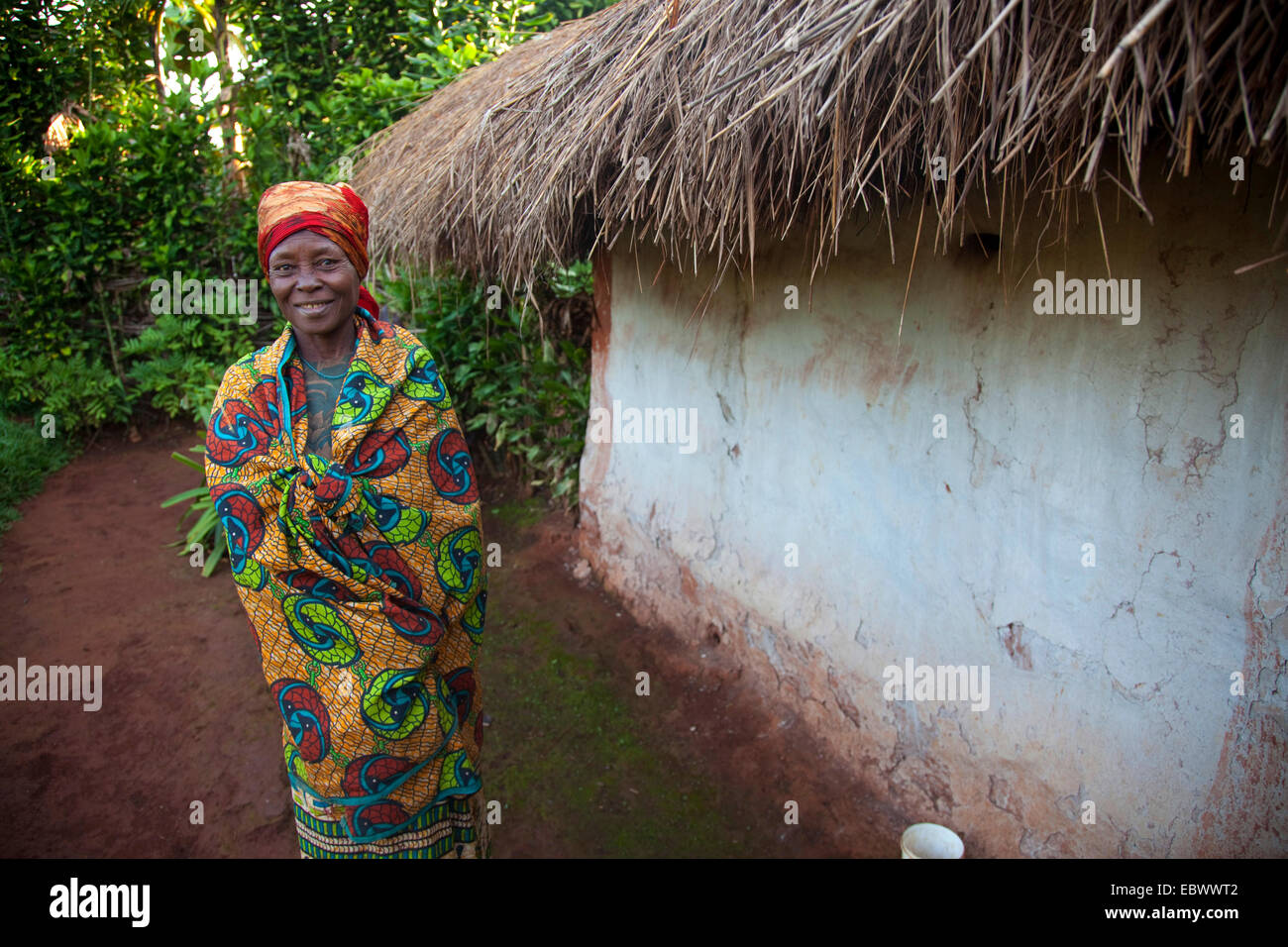 Vecchia donna sospettati di essere una strega del suo villaggio è in piedi accanto al suo umile casa con tetto di paglia, Burundi, vicino al Parco Nazionale de la Ruvubu, Cankuzo Foto Stock