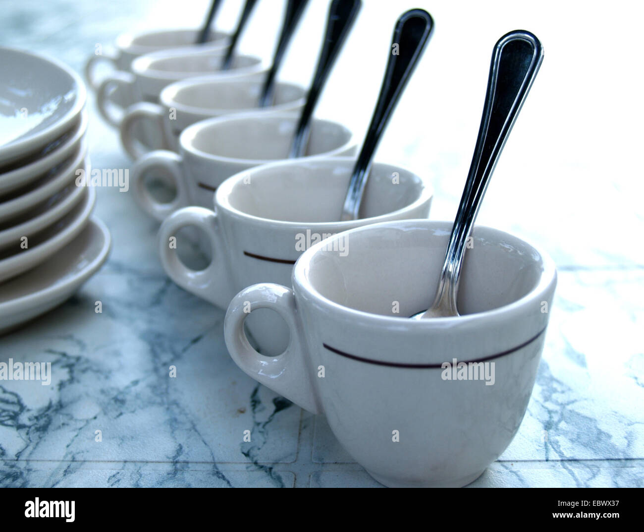 Tazze da caffè in una fila con cucchiai Foto Stock