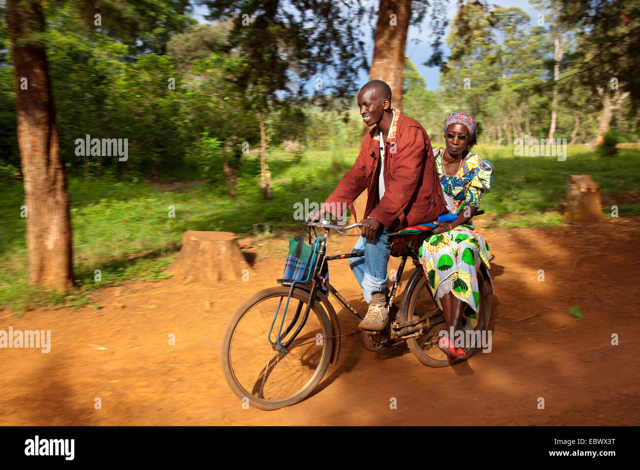Uomo in sella a una moto con una donna in tradizionali abiti africani sul vettore, Burundi, Cankuzo, vicino al Parco Nazionale de la Ruvubu, Cankuzo Foto Stock