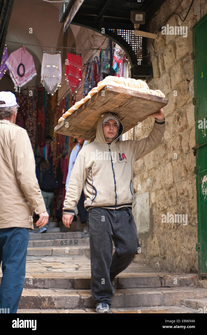 Giovane uomo il trasporto di pane sulla sua testa attraverso la città vecchia, Israele, Gerusalemme Foto Stock