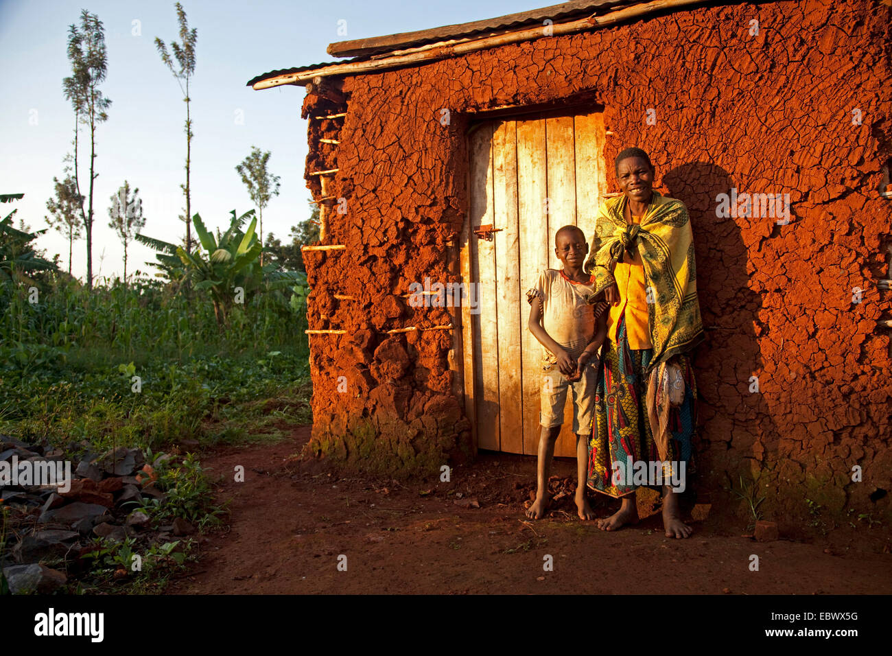La madre e il figlio in piedi nella parte anteriore del fango in casa la mattina presto, Burundi, Cancuzo, Cankuzo Foto Stock